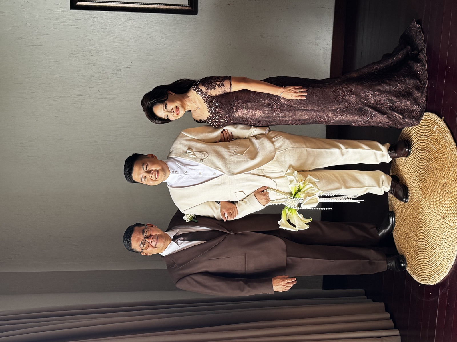 Groom standing with parents in wedding attire