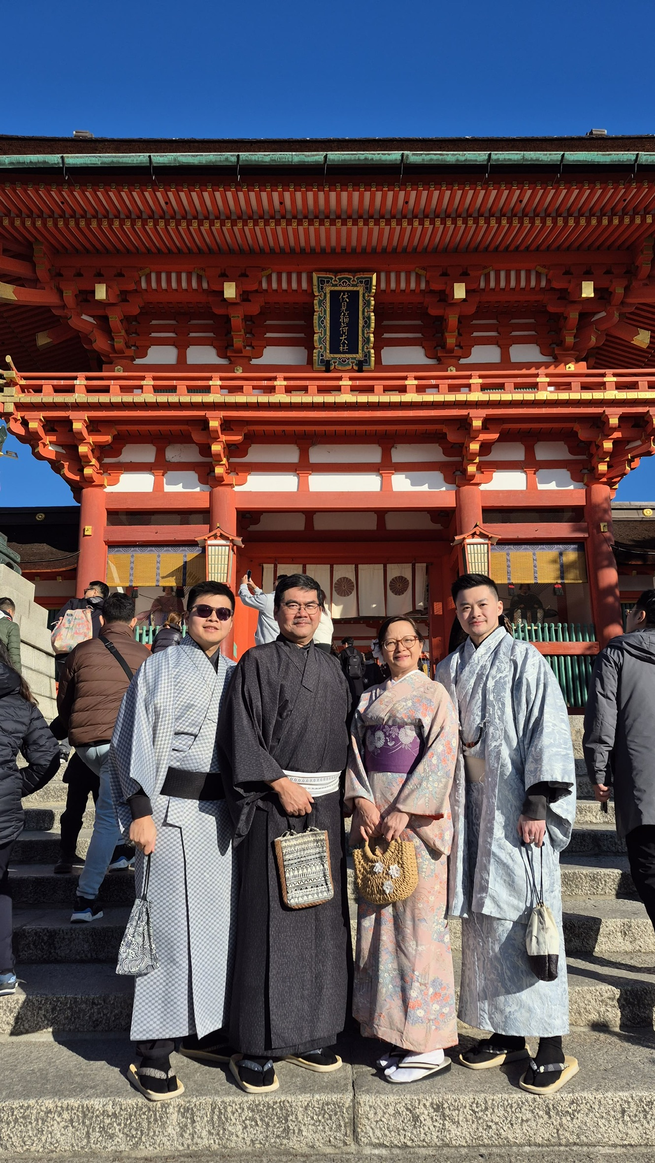 Family in kimonos standing in front of the red Fushimi Inari shrine gate