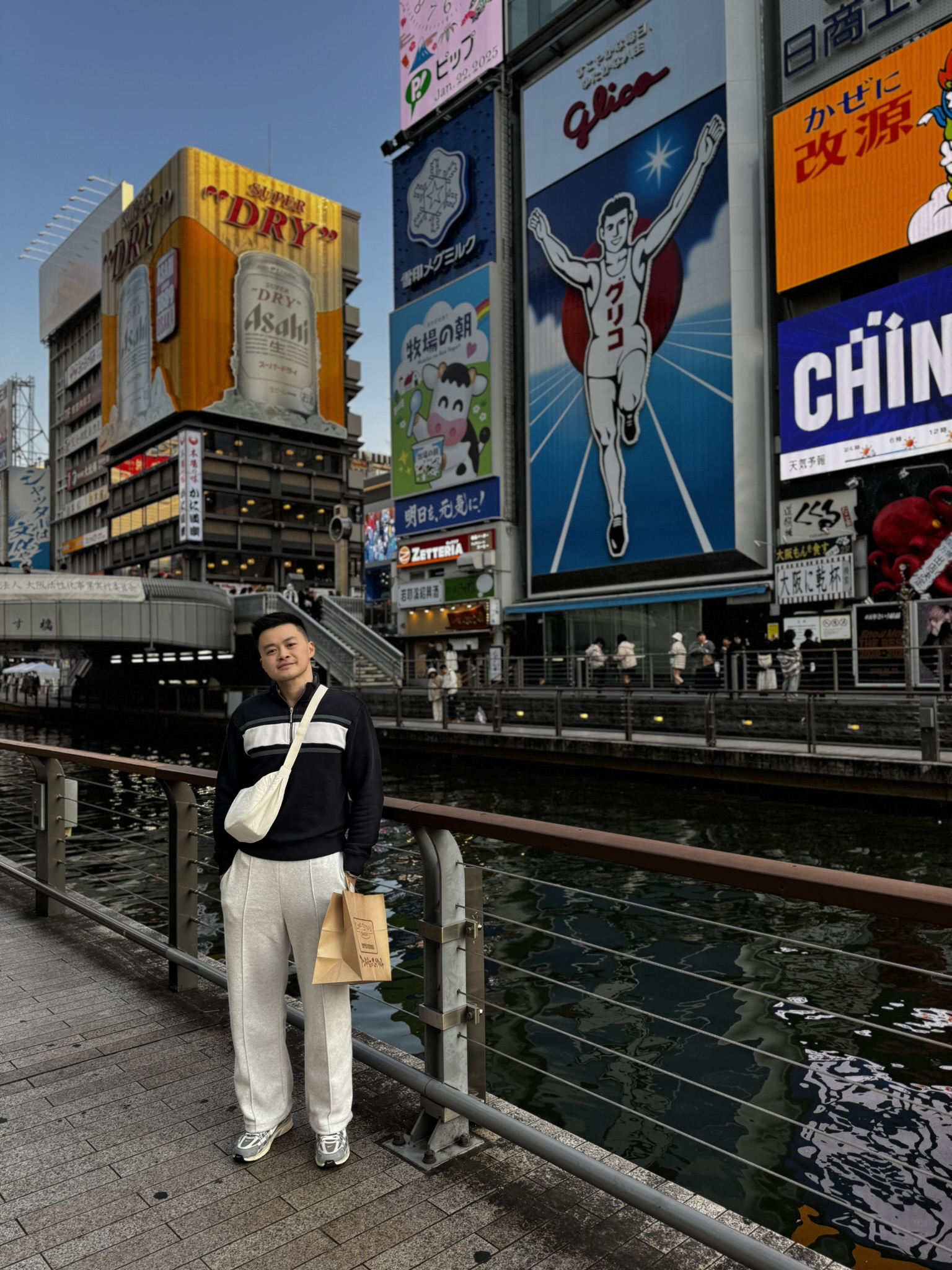 Portrait by the Dotonbori canal with the Glico sign in Osaka