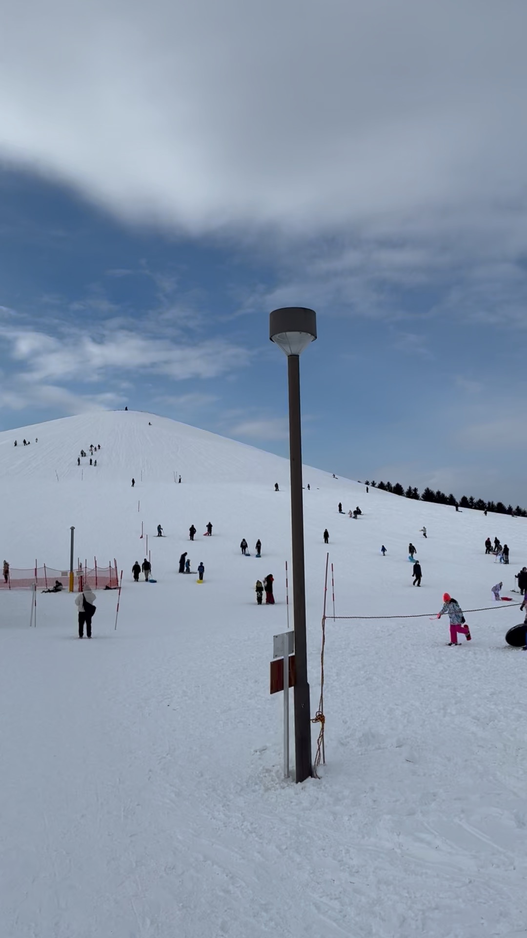 Families playing on a snowy hill at Moerenuma Park