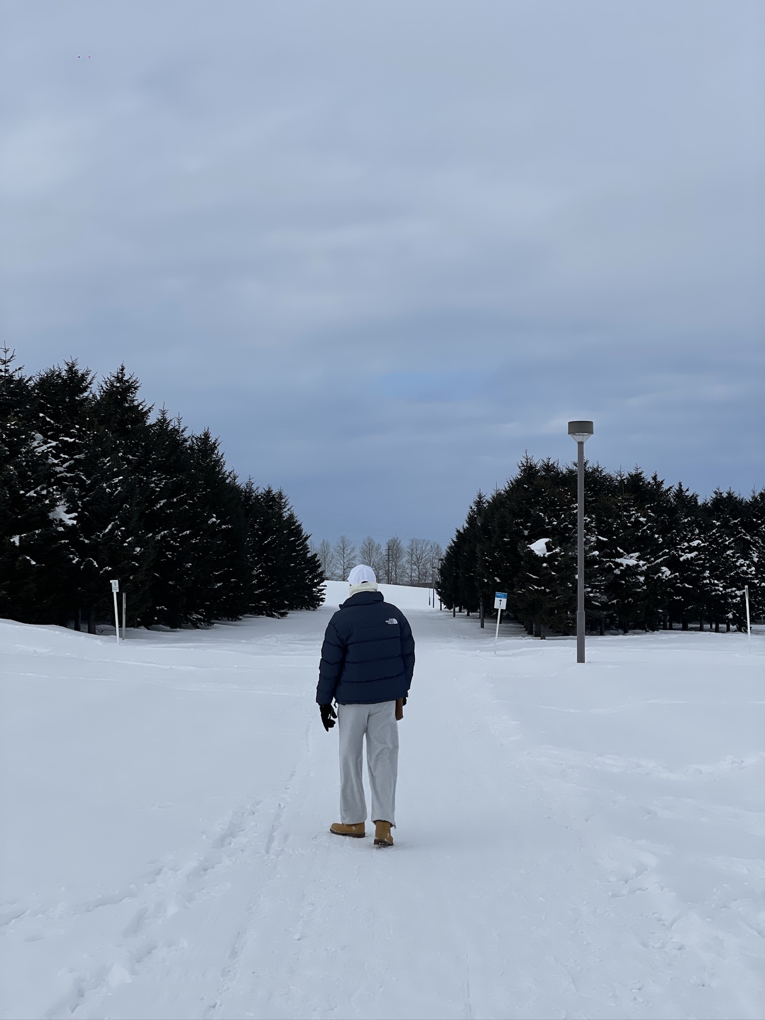 Walking through deep snow between trees at Moerenuma Park