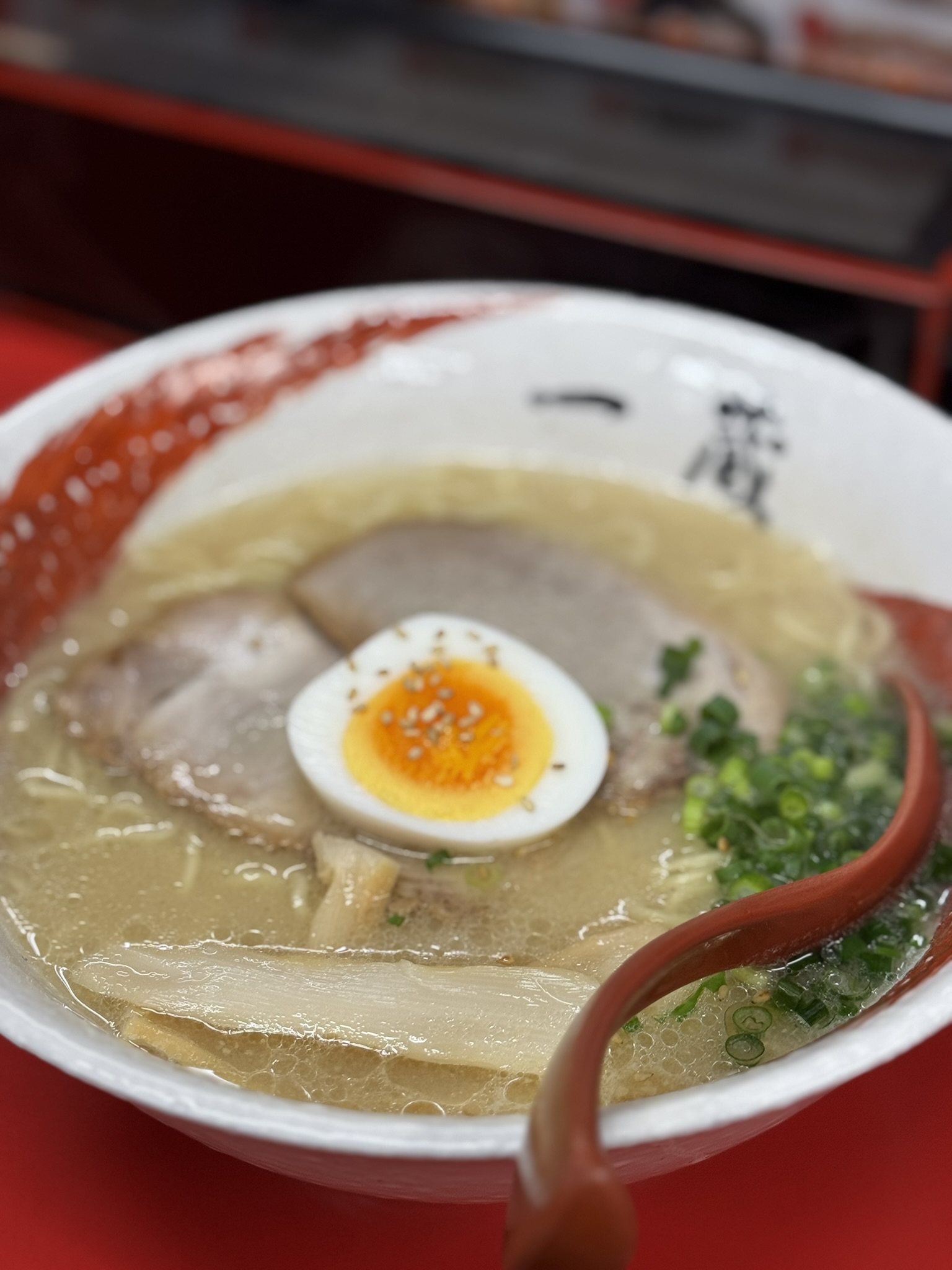 A bowl of ramen with egg, pork, scallions, and savoury broth