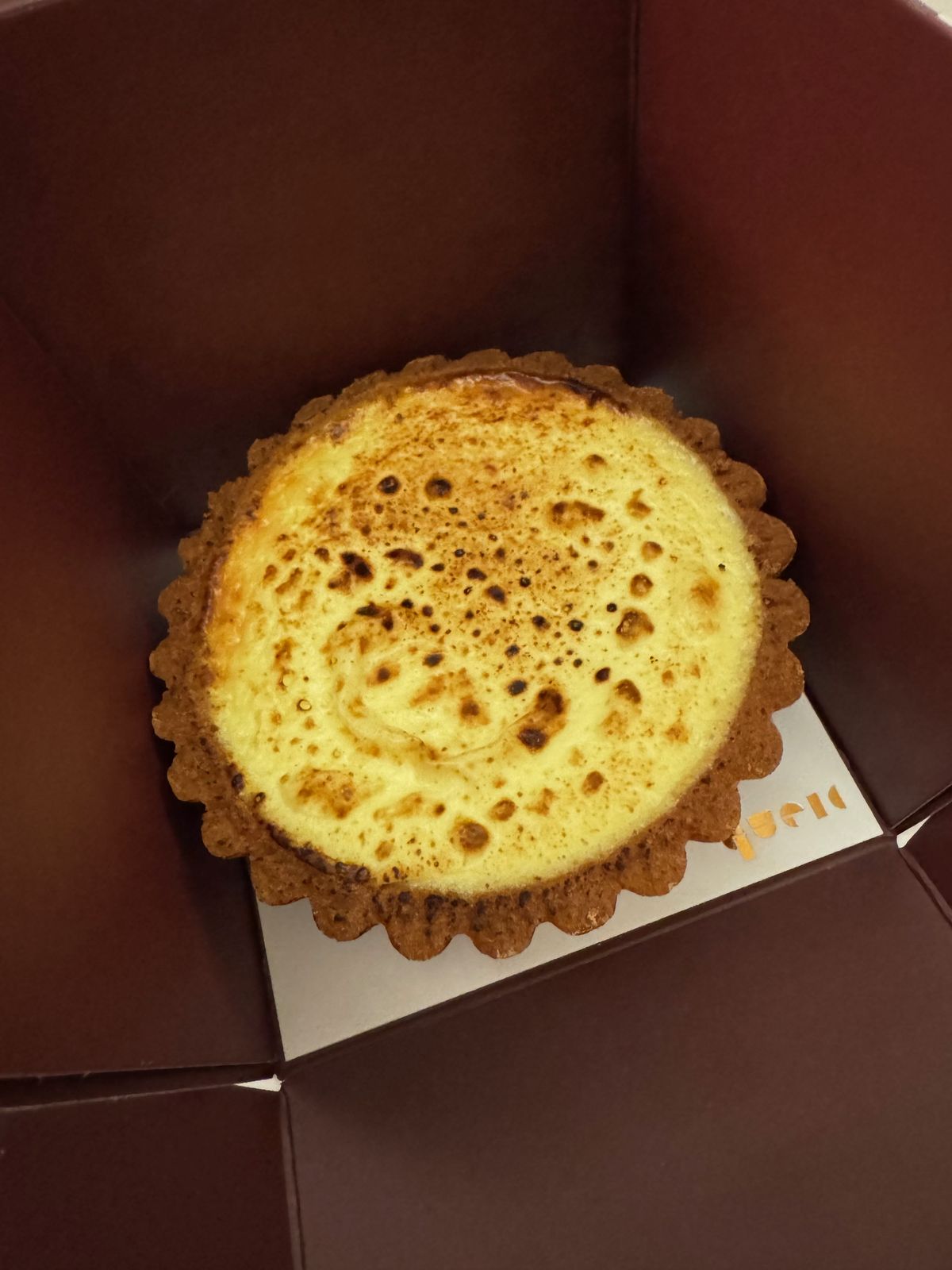 Burnt-top cheesecake in an open box on a bed at night